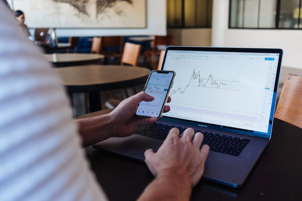 order book imbalance — person using smartphone and MacBook Pro