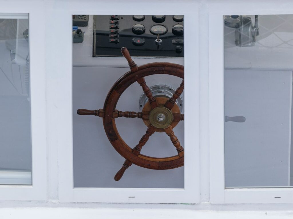 github actions — A wooden ship wheel in the wheelhouse of a fishing vessel